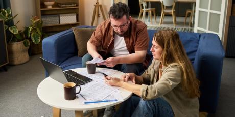 Mann und Frau am Tisch schauen auf Papiere